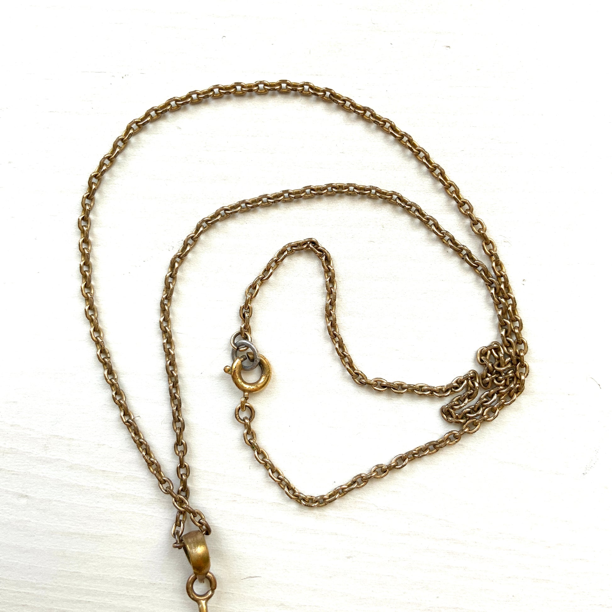 An antique pendant necklace featuring a starburst design with a mysterious glass stone known as Saphiret set in the centre. 神秘的な輝きを放つサフィレットを中央に添えた、ラインストーンのスターバーストデザインのペンダントネックレス。