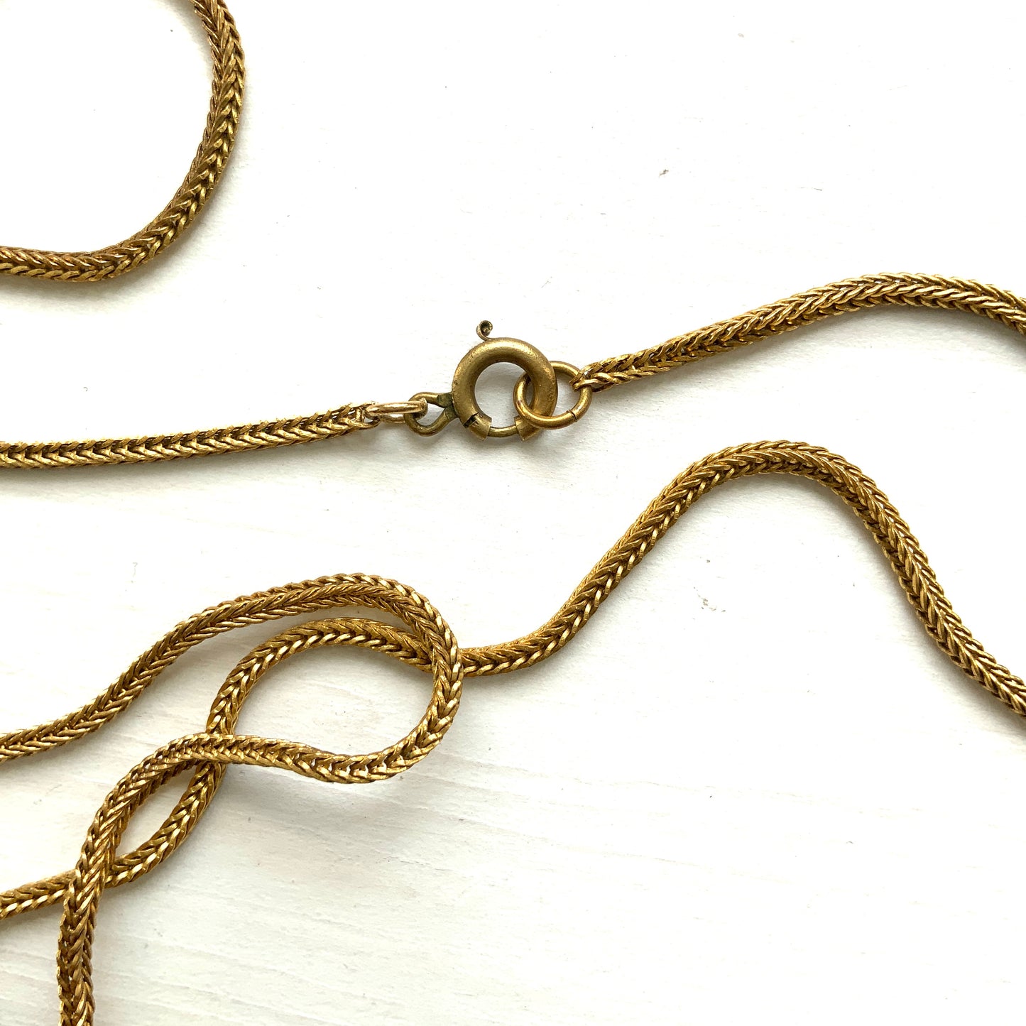 A lavaliere necklace featuring beautifully banded brown and white agate, paired with a gold-tone charm. ブラウンとホワイトの縞模様が美しいメノウと、ゴールドトーンのチャームが組み合わされたラヴァリエネックレス。