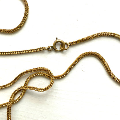 A lavaliere necklace featuring beautifully banded brown and white agate, paired with a gold-tone charm. ブラウンとホワイトの縞模様が美しいメノウと、ゴールドトーンのチャームが組み合わされたラヴァリエネックレス。