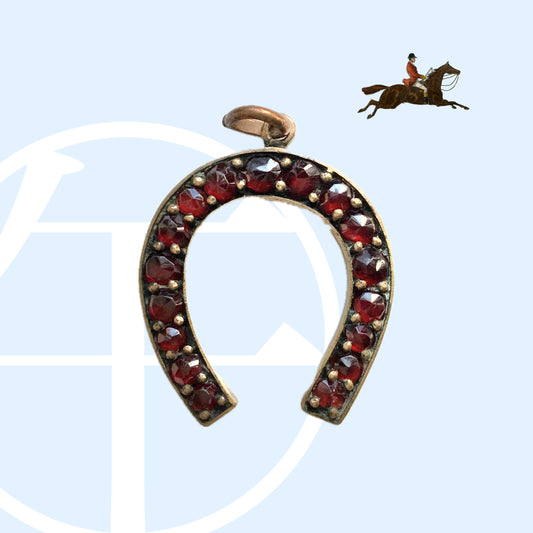 A Victorian horseshoe charm set with garnets. ガーネットが連なる、ヴィクトリア時代の馬蹄モチーフチャーム。