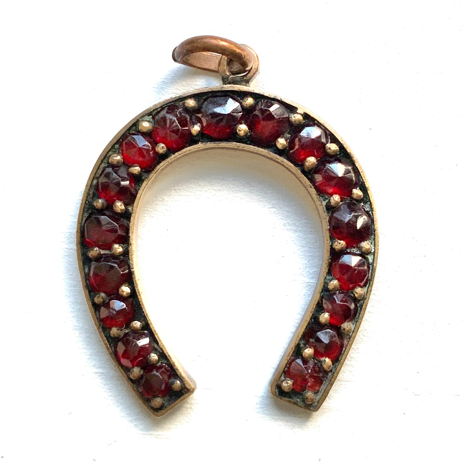 A Victorian horseshoe charm set with garnets. ガーネットが連なる、ヴィクトリア時代の馬蹄モチーフチャーム。