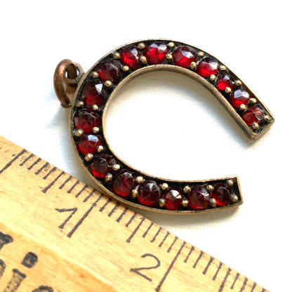 A Victorian horseshoe charm set with garnets. ガーネットが連なる、ヴィクトリア時代の馬蹄モチーフチャーム。