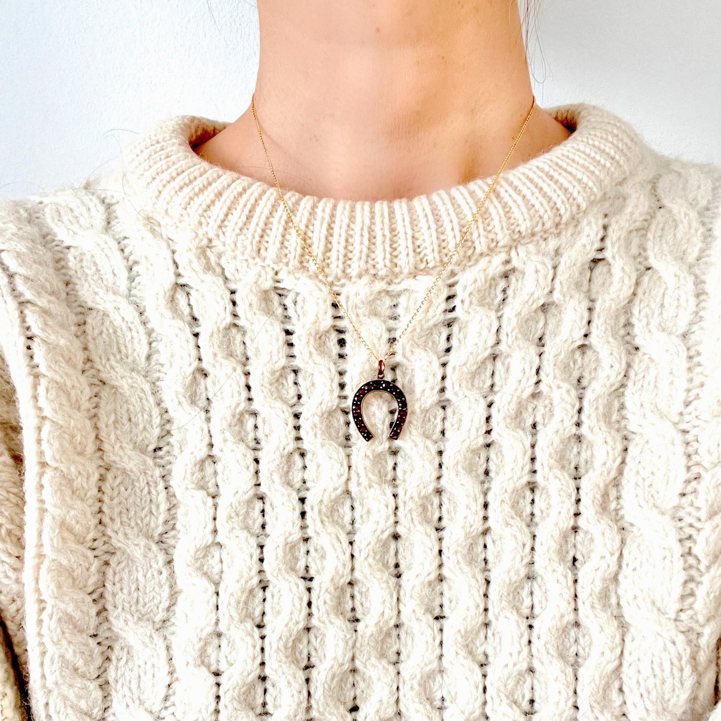 A Victorian horseshoe charm set with garnets. ガーネットが連なる、ヴィクトリア時代の馬蹄モチーフチャーム。