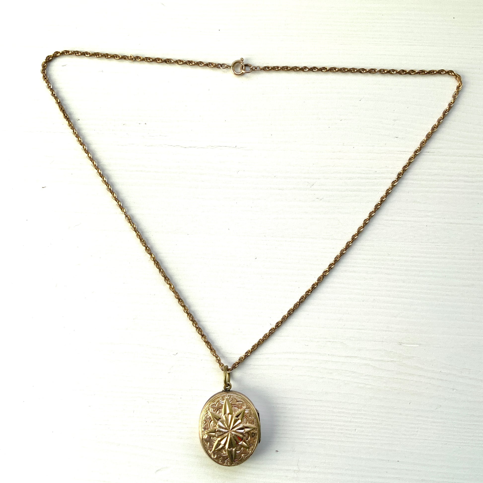 A rolled gold locket pendant necklace featuring a beautifully embossed starburst motif. スターバーストモチーフが立体的にエンボスされた、ロールドゴールドのロケットペンダントネックレス。