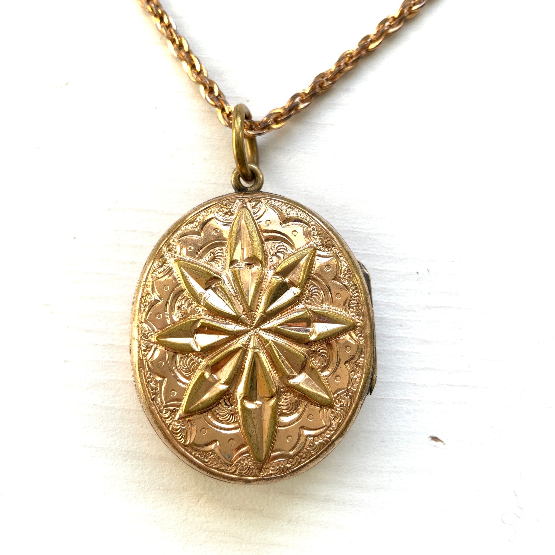 A rolled gold locket pendant necklace featuring a beautifully embossed starburst motif. スターバーストモチーフが立体的にエンボスされた、ロールドゴールドのロケットペンダントネックレス。