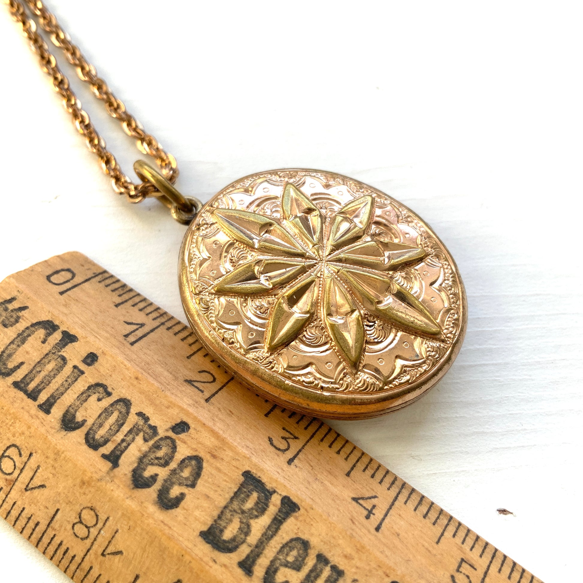 A rolled gold locket pendant necklace featuring a beautifully embossed starburst motif. スターバーストモチーフが立体的にエンボスされた、ロールドゴールドのロケットペンダントネックレス。