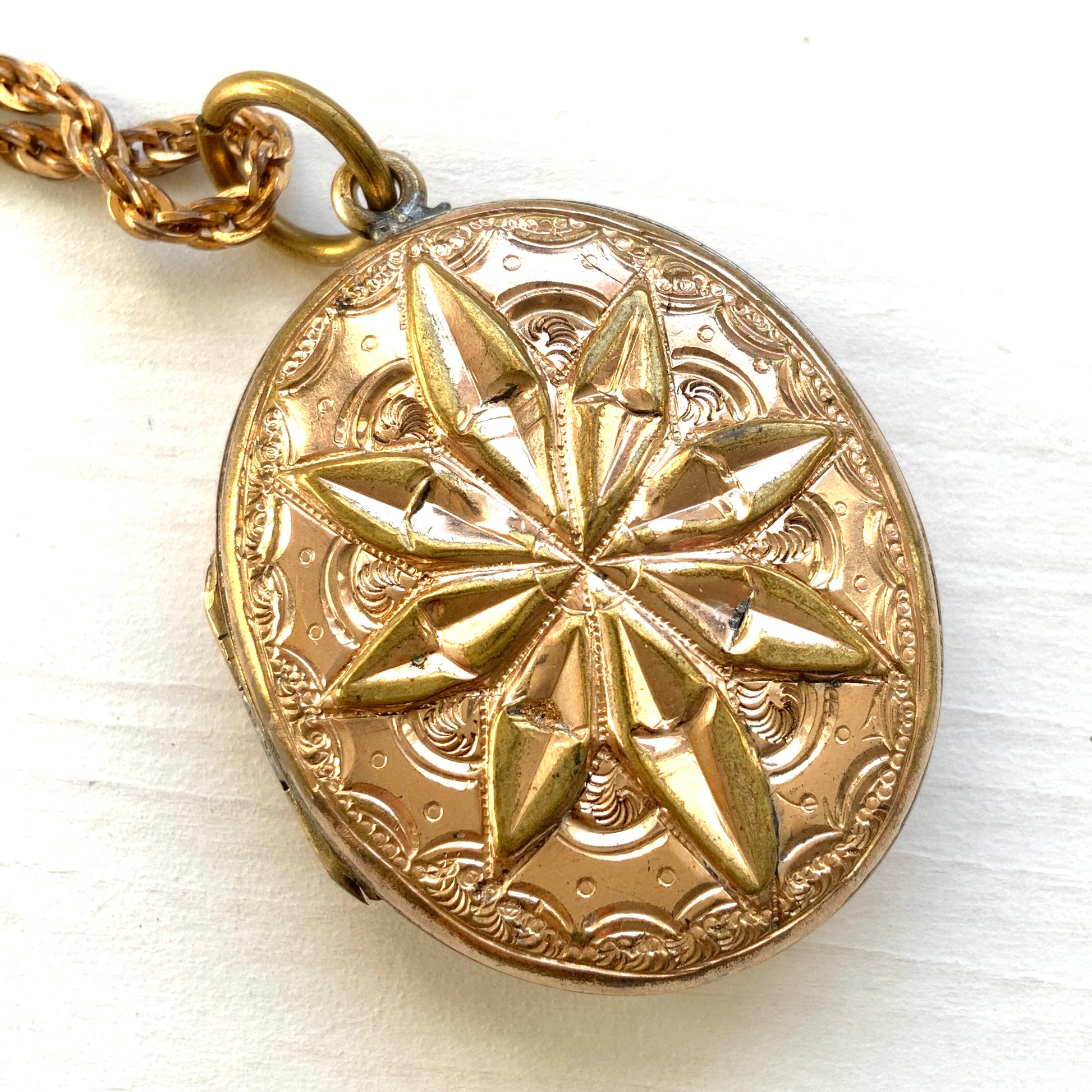 A rolled gold locket pendant necklace featuring a beautifully embossed starburst motif. スターバーストモチーフが立体的にエンボスされた、ロールドゴールドのロケットペンダントネックレス。