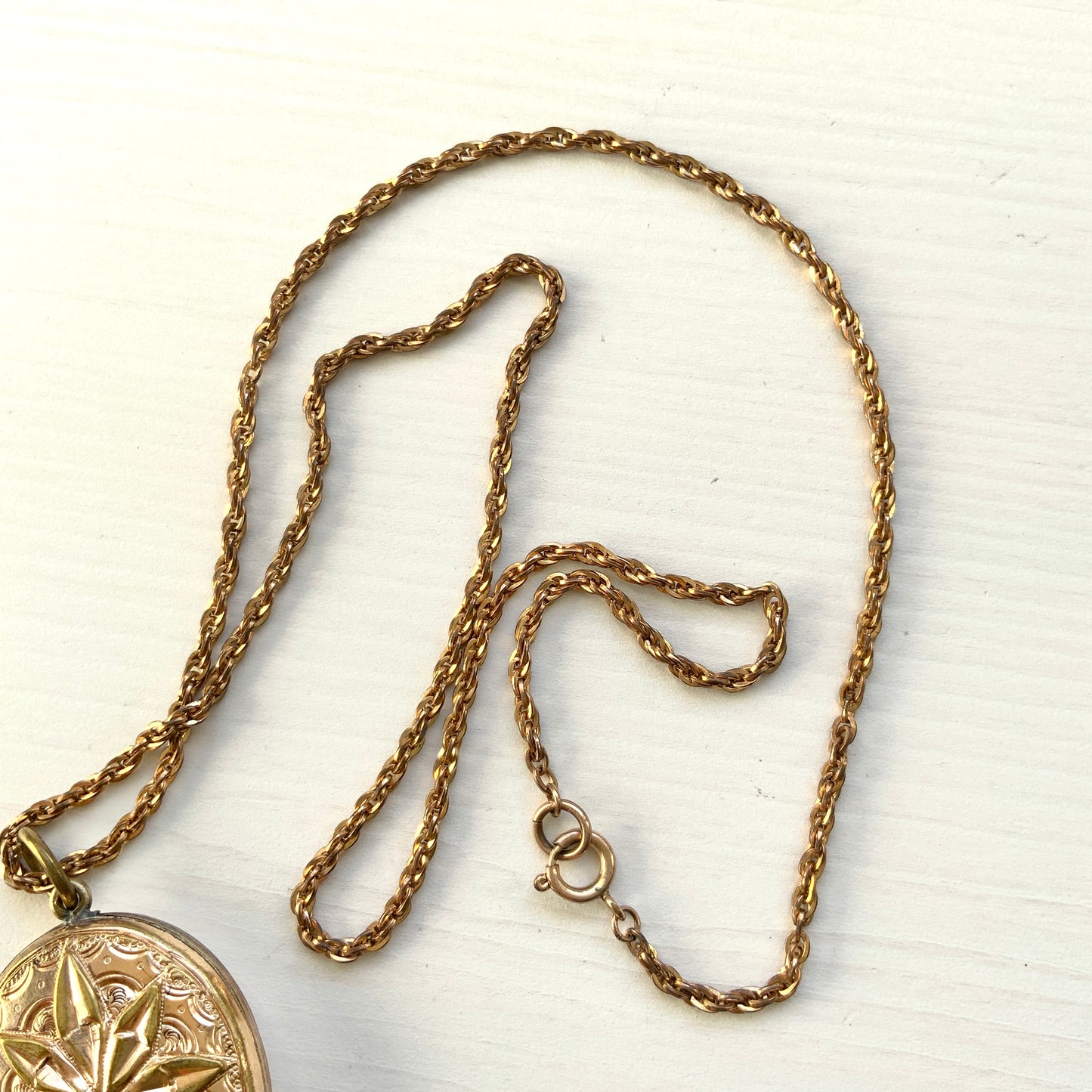 A rolled gold locket pendant necklace featuring a beautifully embossed starburst motif. スターバーストモチーフが立体的にエンボスされた、ロールドゴールドのロケットペンダントネックレス。