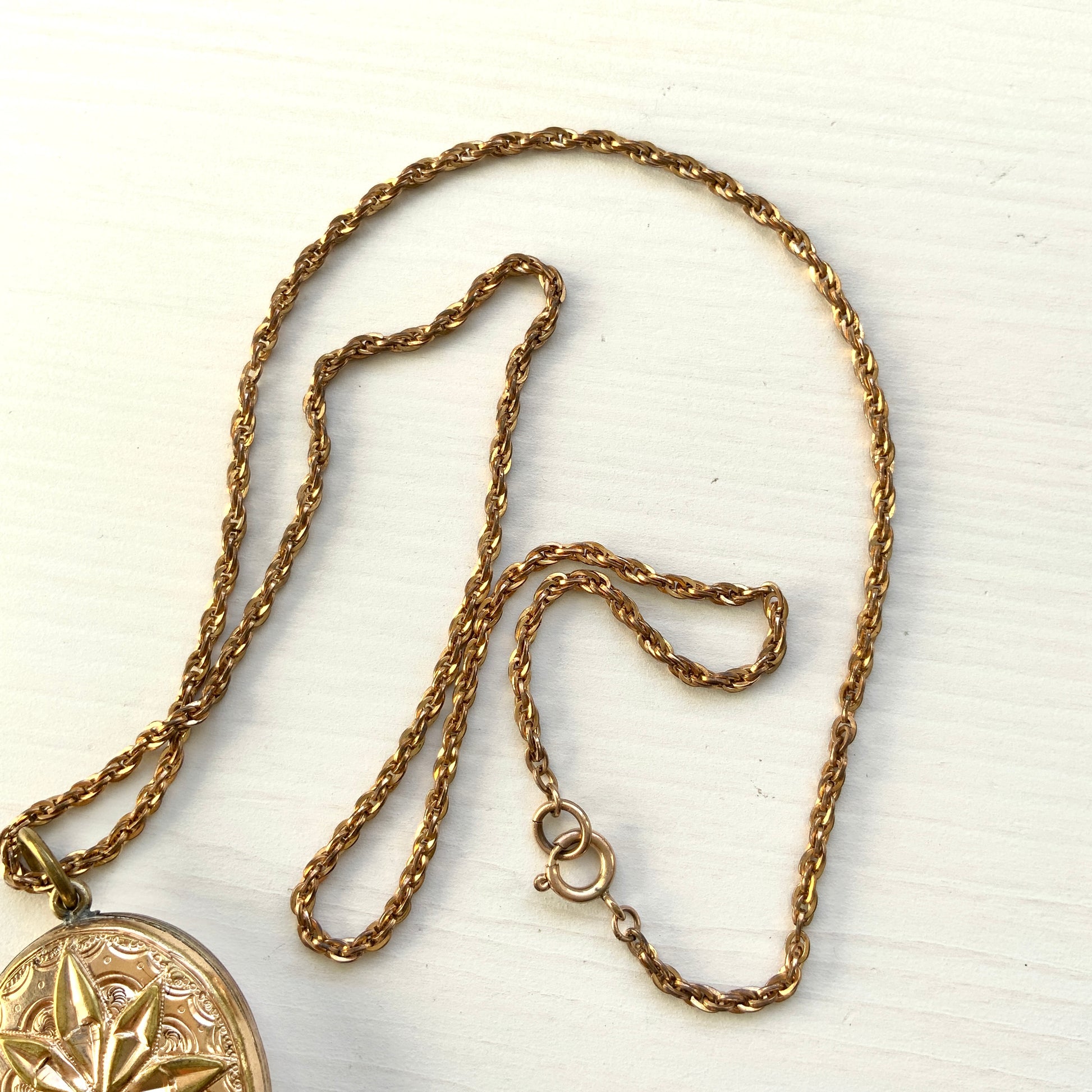 A rolled gold locket pendant necklace featuring a beautifully embossed starburst motif. スターバーストモチーフが立体的にエンボスされた、ロールドゴールドのロケットペンダントネックレス。