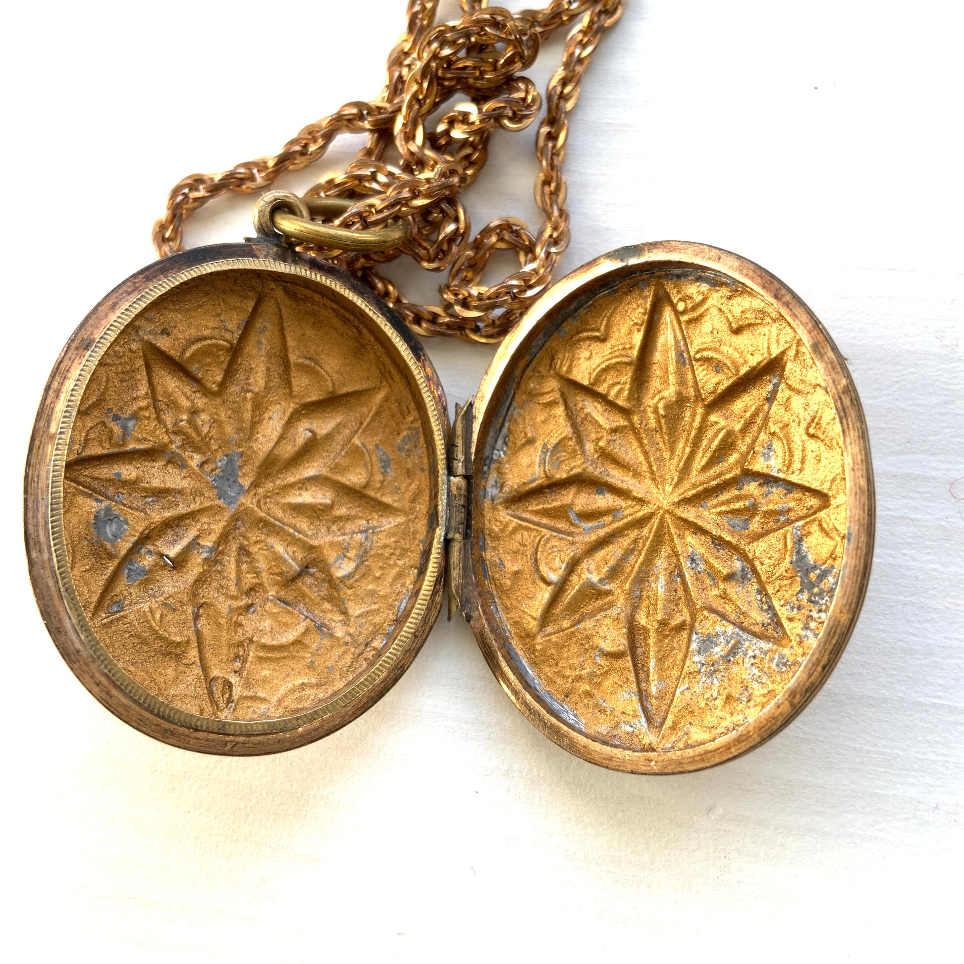 A rolled gold locket pendant necklace featuring a beautifully embossed starburst motif. スターバーストモチーフが立体的にエンボスされた、ロールドゴールドのロケットペンダントネックレス。