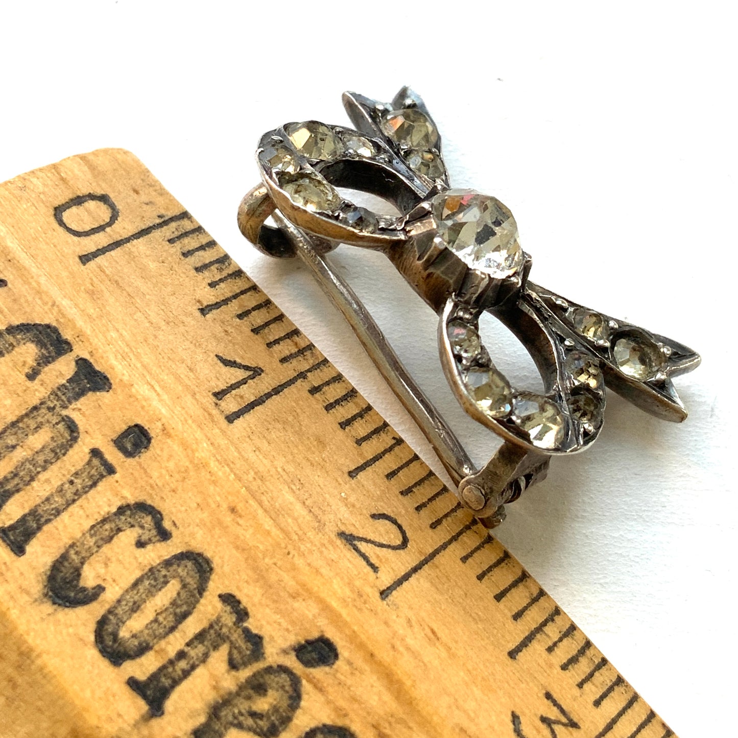 A small silver bow brooch set with rhinestones. ラインストーンがあしらわれた小さなリボンのシルバーブローチ。