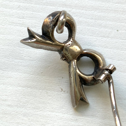 A small silver bow brooch set with rhinestones. ラインストーンがあしらわれた小さなリボンのシルバーブローチ。