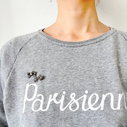 A small silver bow brooch set with rhinestones. ラインストーンがあしらわれた小さなリボンのシルバーブローチ。