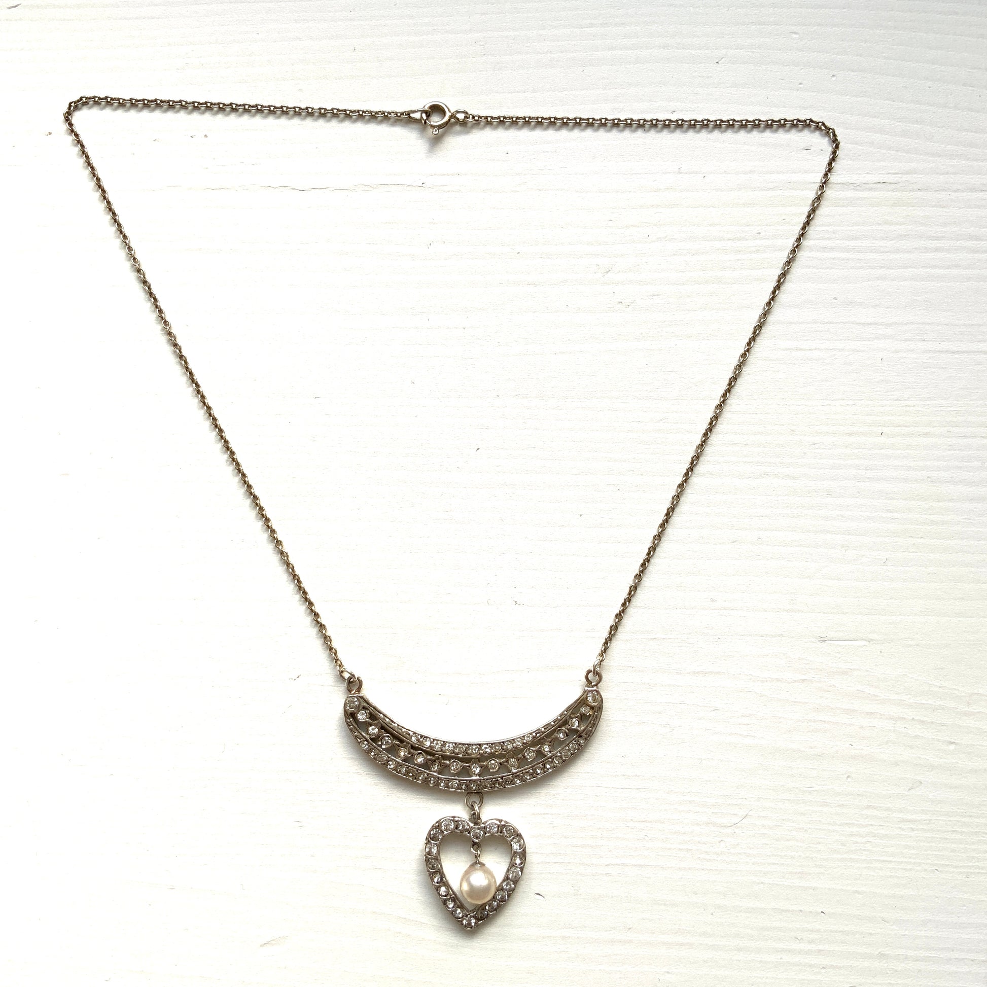A silver pendant necklace featuring a crescent bar and heart motif.  クレセントバーとハートモチーフのシルバーペンダントネックレス。 