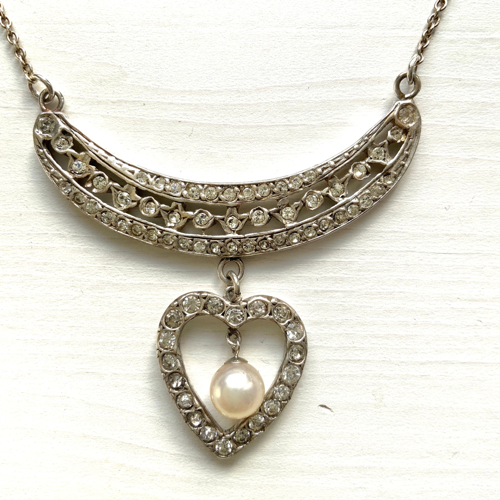 A silver pendant necklace featuring a crescent bar and heart motif.  クレセントバーとハートモチーフのシルバーペンダントネックレス。 