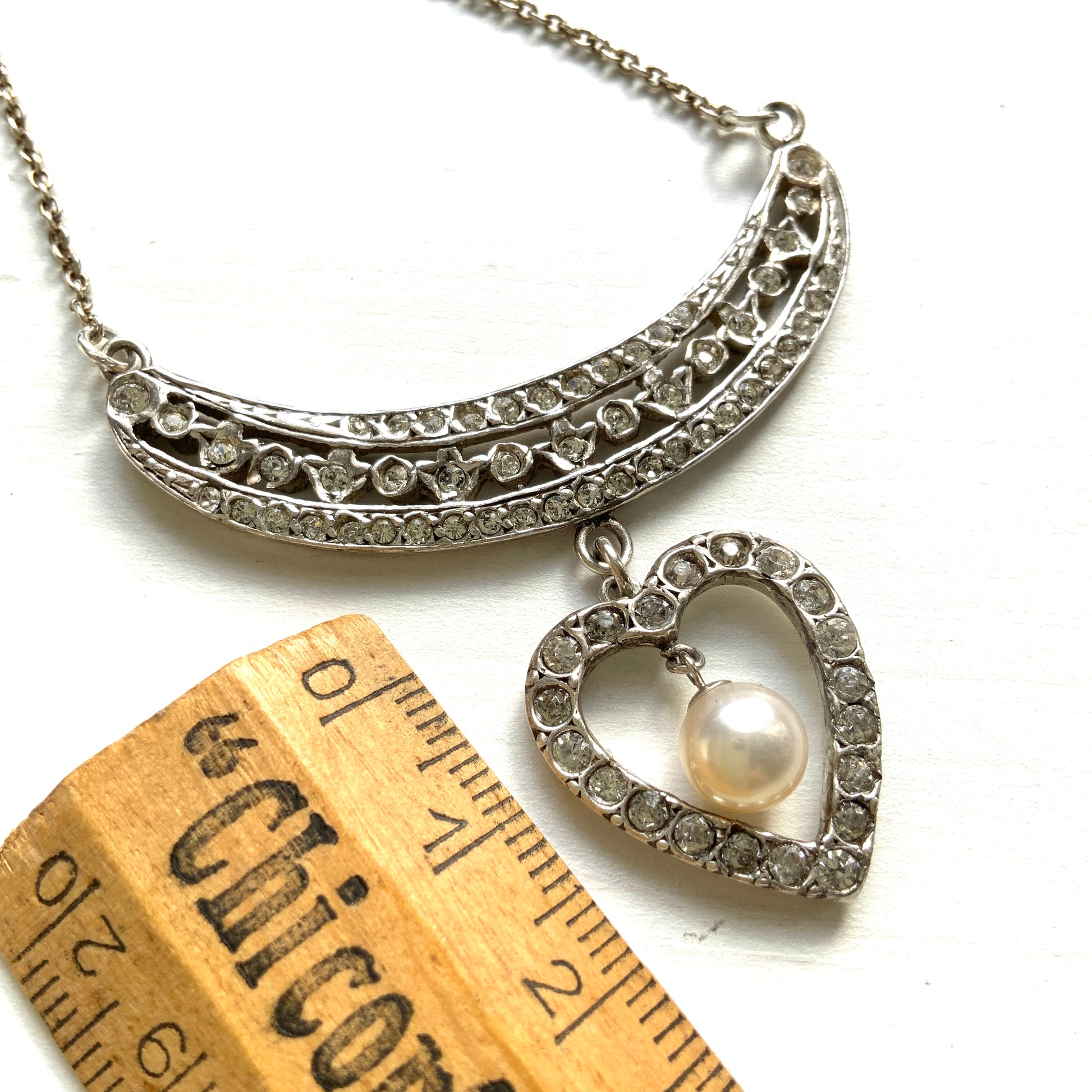 A silver pendant necklace featuring a crescent bar and heart motif.  クレセントバーとハートモチーフのシルバーペンダントネックレス。 