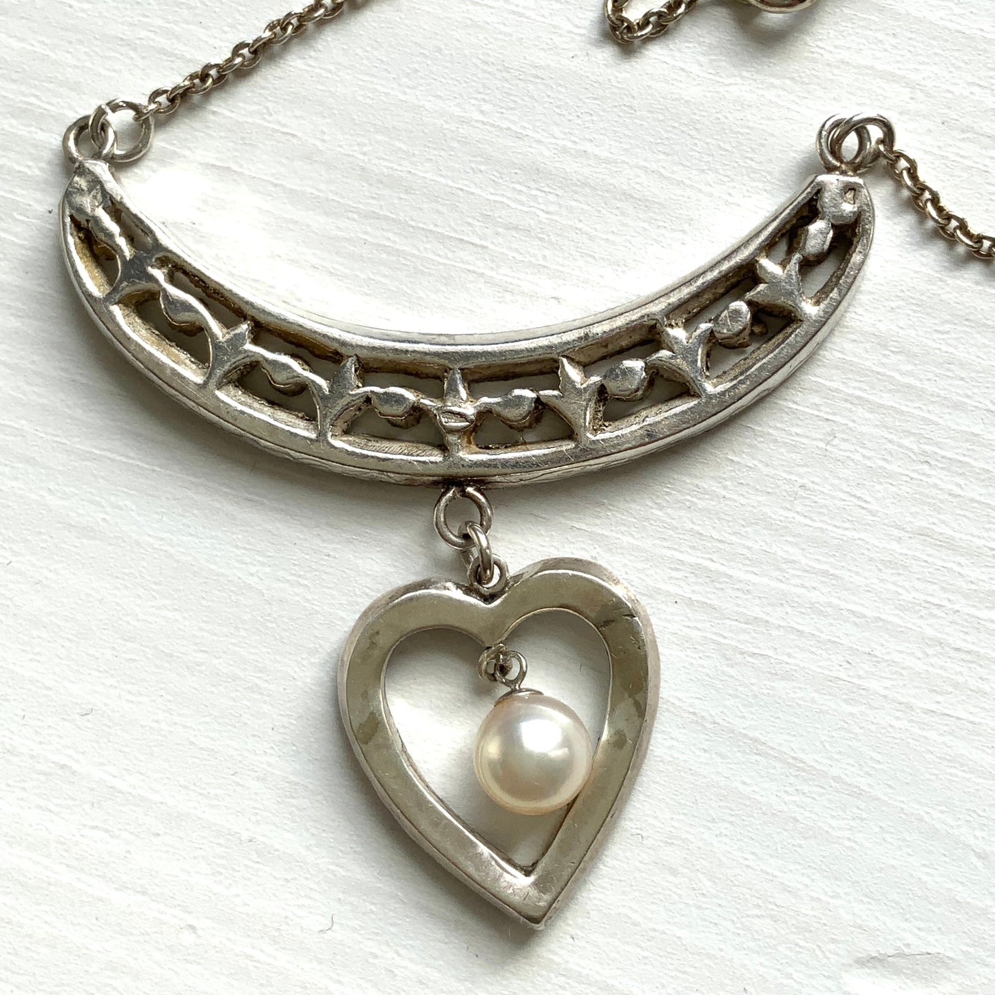 A silver pendant necklace featuring a crescent bar and heart motif.  クレセントバーとハートモチーフのシルバーペンダントネックレス。 