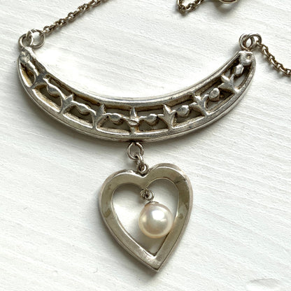 A silver pendant necklace featuring a crescent bar and heart motif.  クレセントバーとハートモチーフのシルバーペンダントネックレス。 