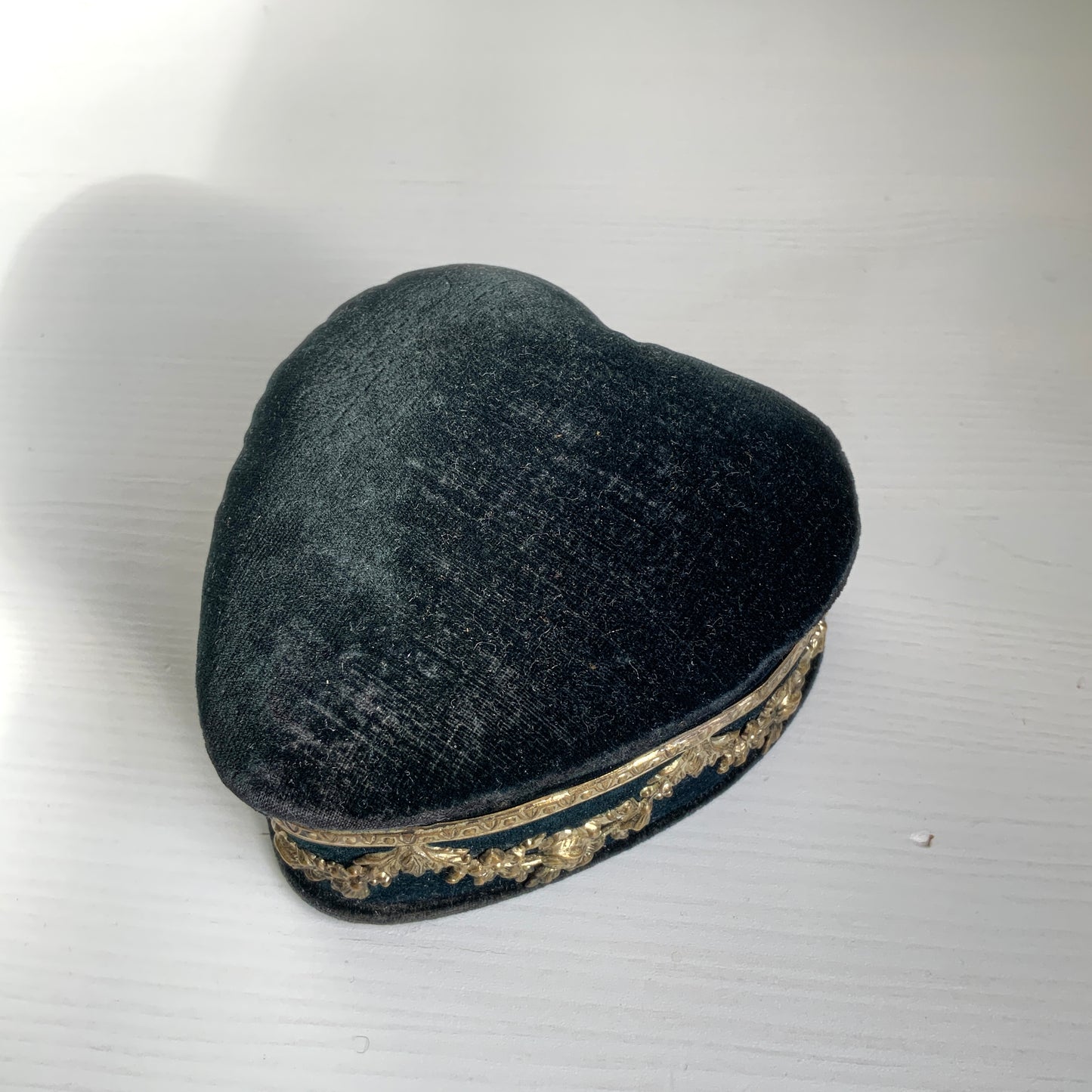 A heart-shaped trinket box featuring delicate silver-tone decoration set against black velvet.  ブラックのベルベットに、繊細なシルバートーンの装飾が映えるハート型の小箱。