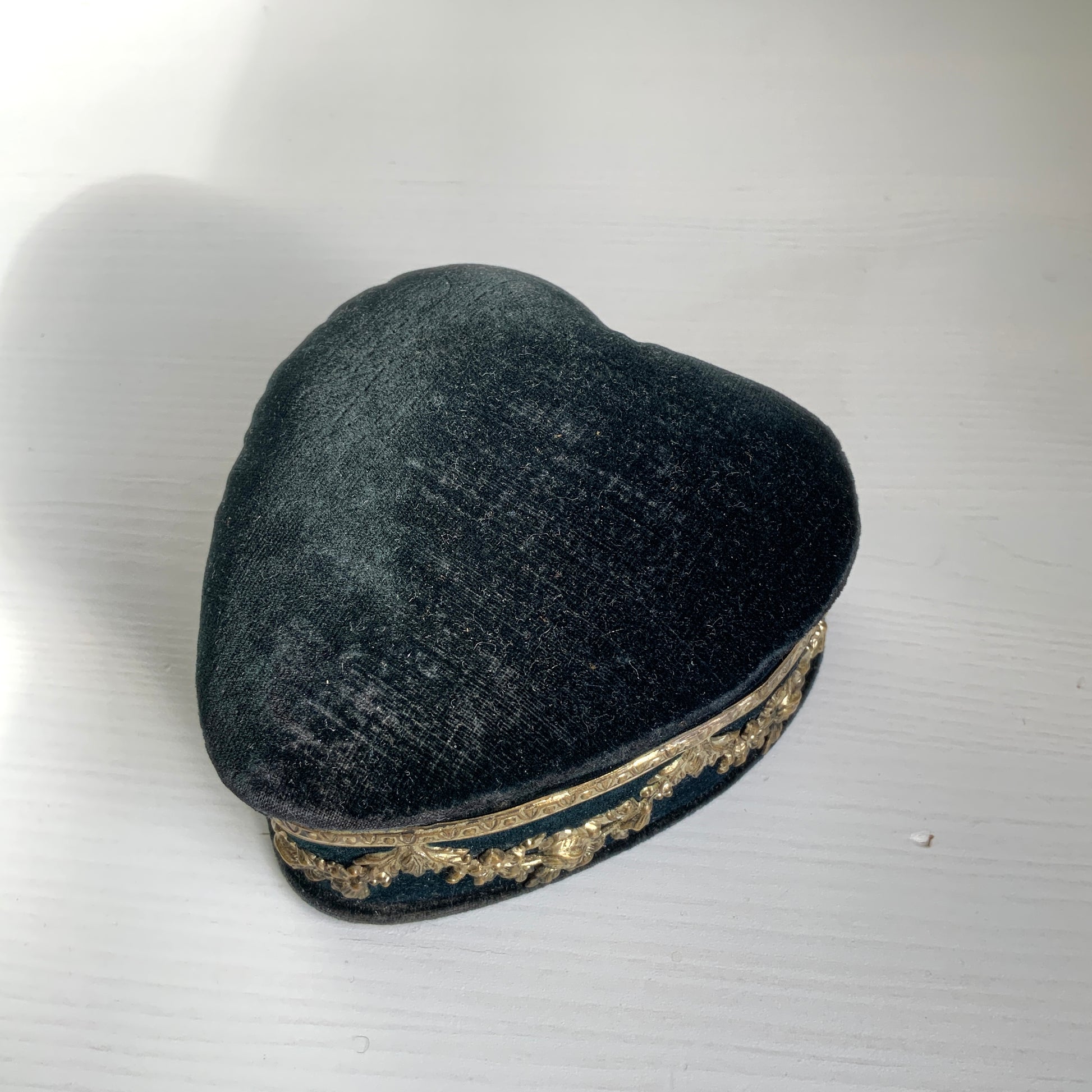A heart-shaped trinket box featuring delicate silver-tone decoration set against black velvet.  ブラックのベルベットに、繊細なシルバートーンの装飾が映えるハート型の小箱。