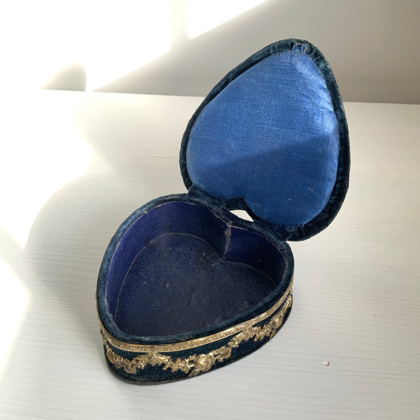 A heart-shaped trinket box featuring delicate silver-tone decoration set against black velvet.  ブラックのベルベットに、繊細なシルバートーンの装飾が映えるハート型の小箱。