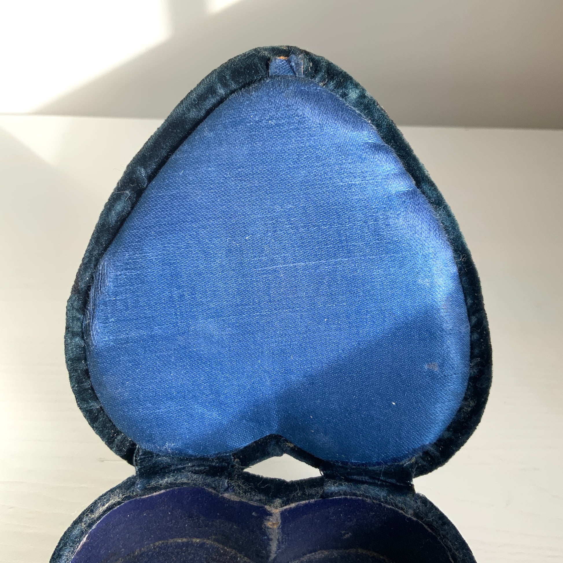 A heart-shaped trinket box featuring delicate silver-tone decoration set against black velvet.  ブラックのベルベットに、繊細なシルバートーンの装飾が映えるハート型の小箱。