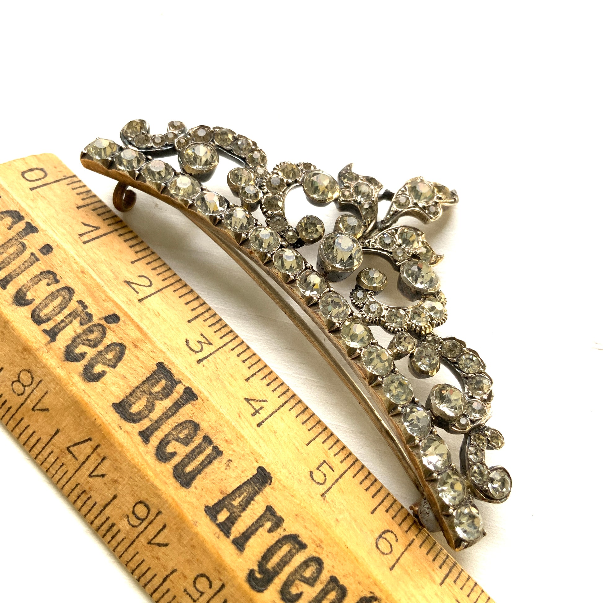 A vintage rhinestone brooch with flowing leaf-like motifs and a gentle curved silhouette.  ラインストーンが連なり、葉っぱのようなモチーフがしなやかに広がるヴィンテージブローチ。 