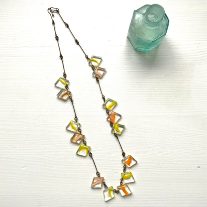 Necklace featuring diamond-shaped clear glass beads infused with shades of yellow, orange, and white. クリアのダイヤ型グラスにイエロー、オレンジ、ホワイトのカラーが入ったビーズを使ったネックレス。 