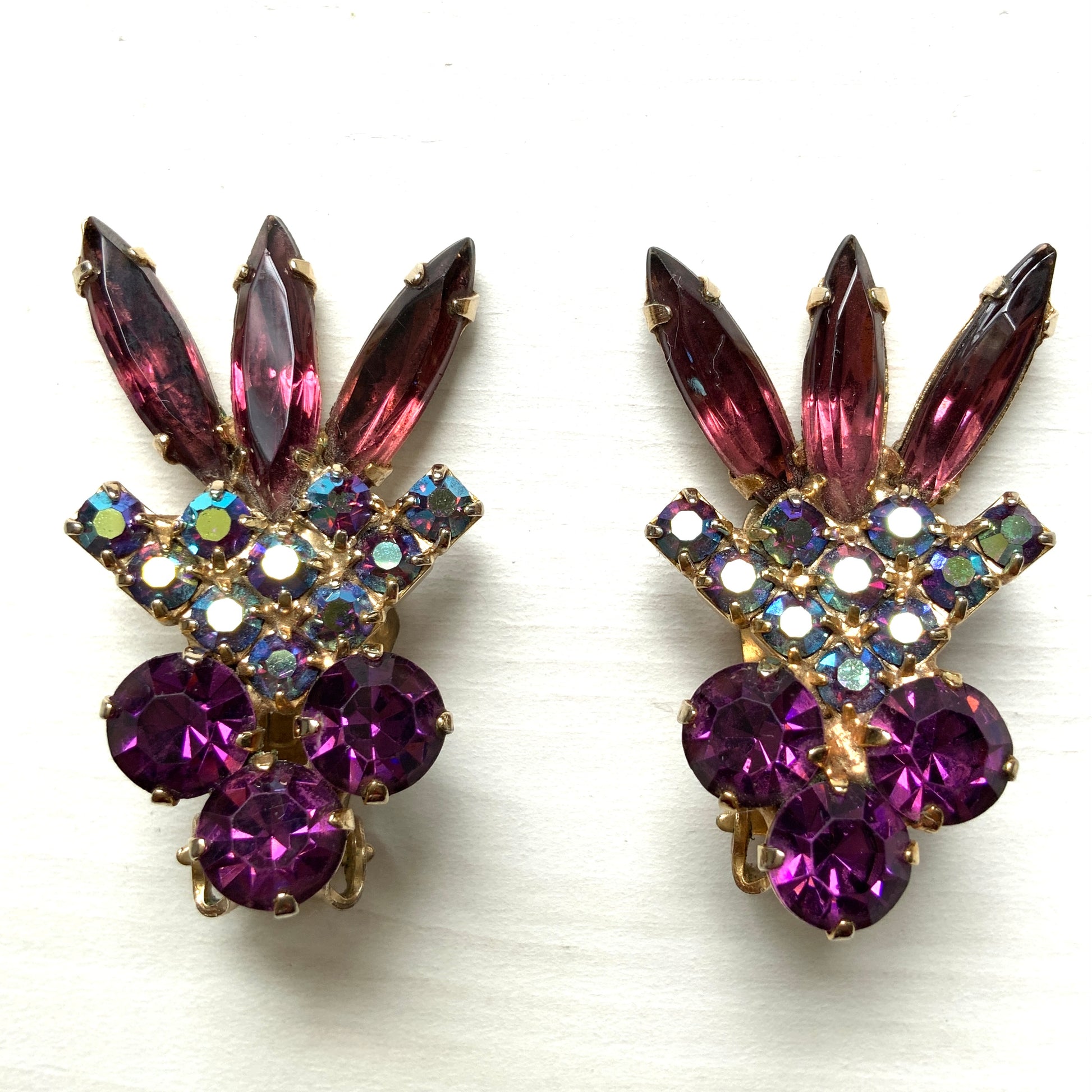 Vintage clip-on earrings featuring amethyst-coloured rhinestones and blue-toned aurora borealis stones.  アメジストカラーのラインストーンとブルーベースのオーロラストーンを組み合わせたヴィンテージのクリップイヤリング。 
