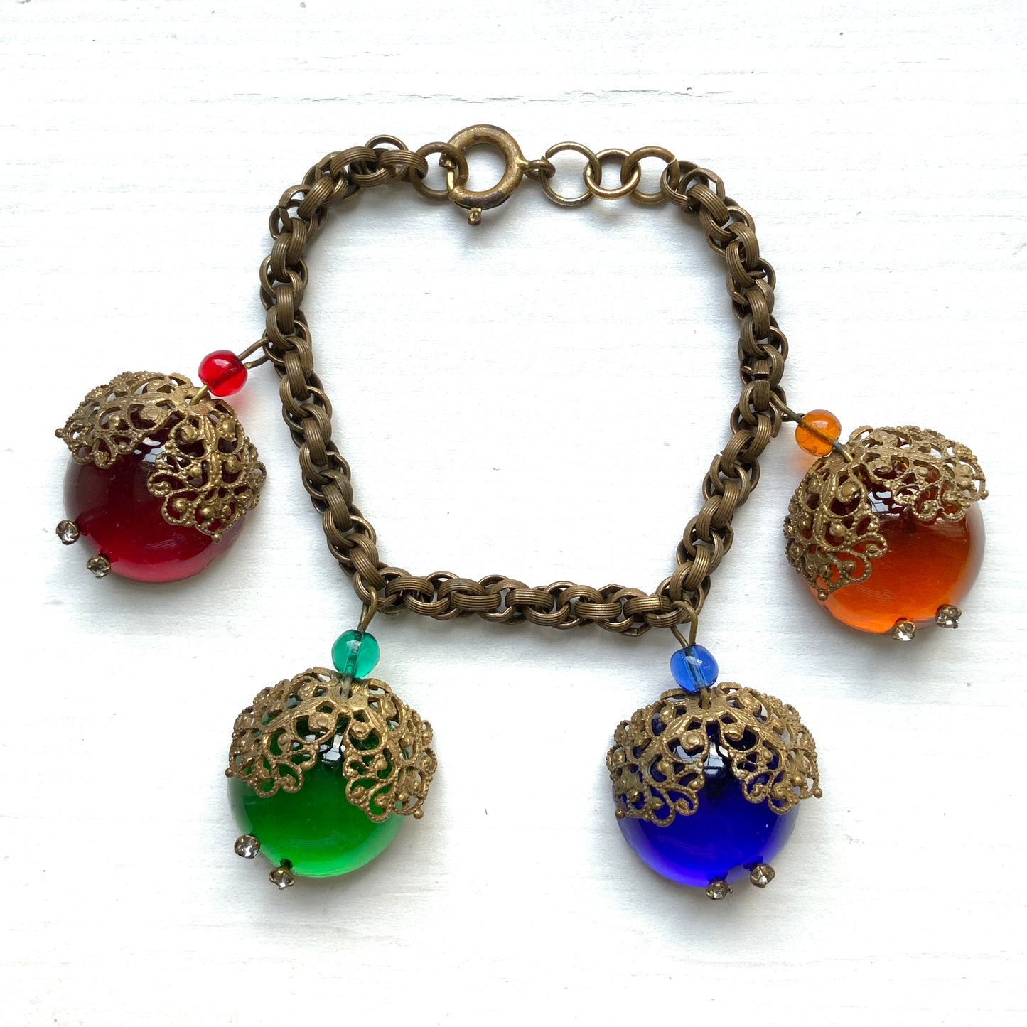 A vintage charm bracelet featuring colourful glass cabochon charms. カラフルなカボションガラスチャームが揺れる、ヴィンテージチャームブレスレット。
