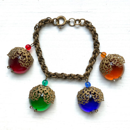 A vintage charm bracelet featuring colourful glass cabochon charms. カラフルなカボションガラスチャームが揺れる、ヴィンテージチャームブレスレット。
