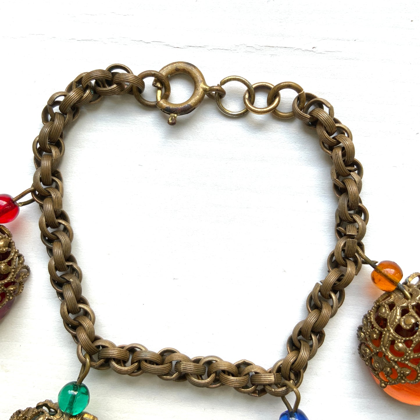 A vintage charm bracelet featuring colourful glass cabochon charms. カラフルなカボションガラスチャームが揺れる、ヴィンテージチャームブレスレット。
