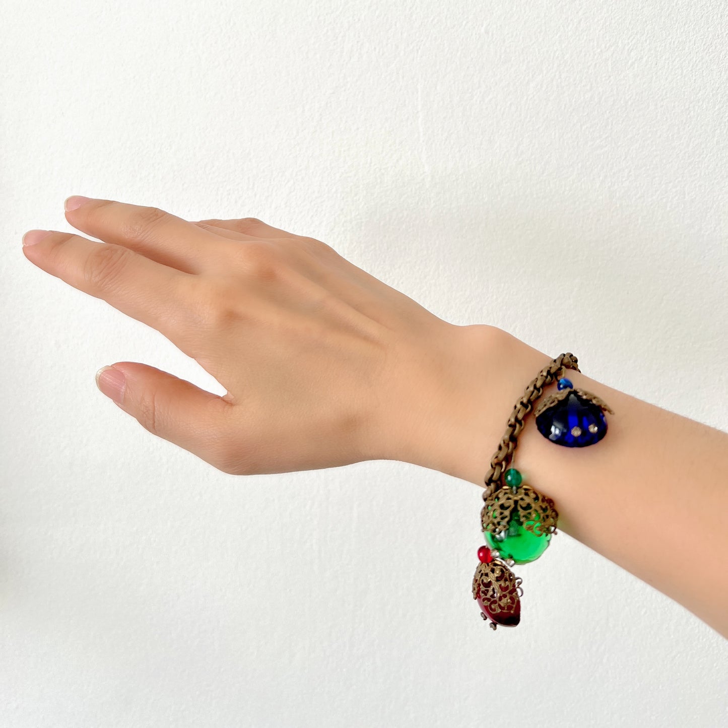 A vintage charm bracelet featuring colourful glass cabochon charms. カラフルなカボションガラスチャームが揺れる、ヴィンテージチャームブレスレット。