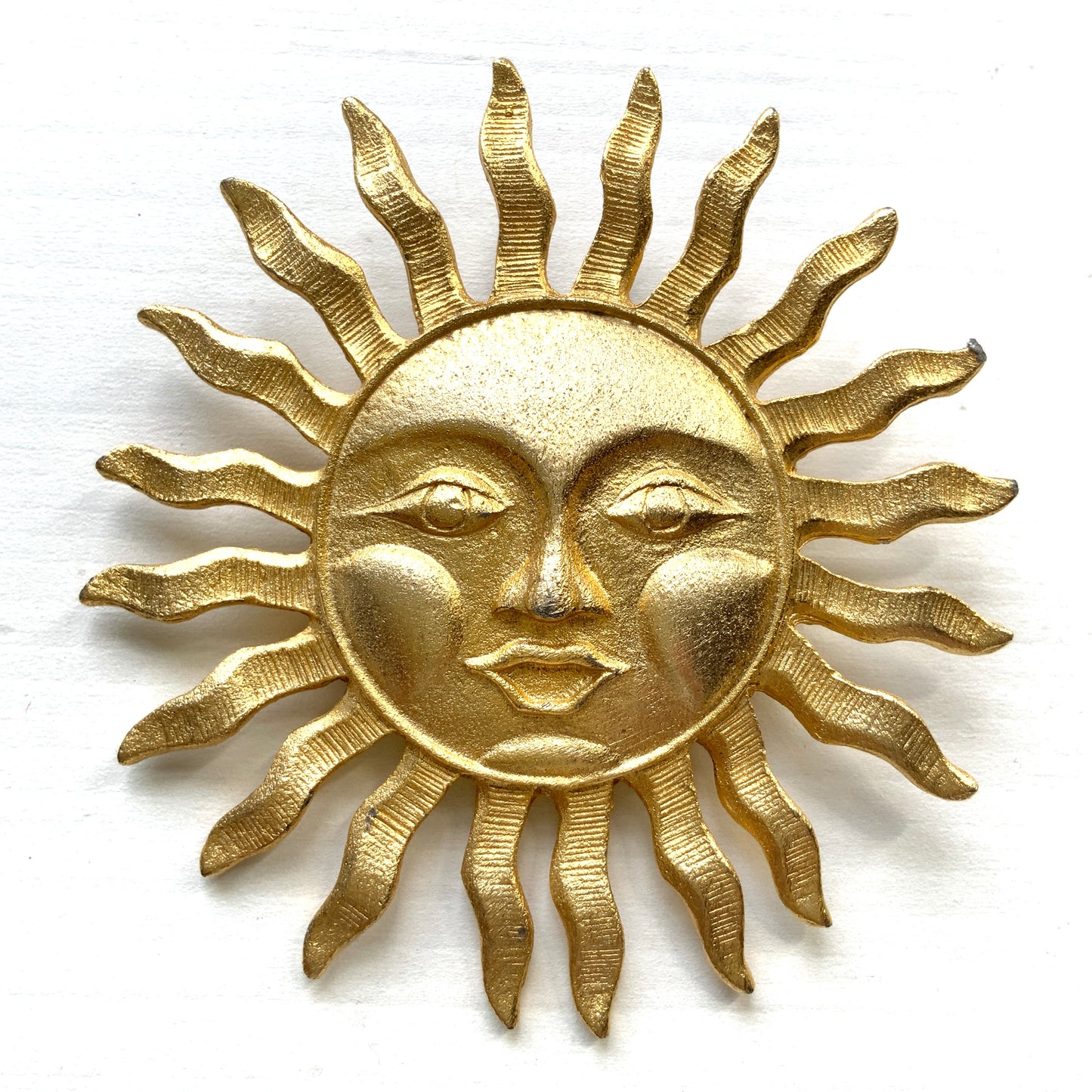 A charming vintage sun brooch featuring a smiling face.  笑顔をたたえた太陽のヴィンテージブローチ。