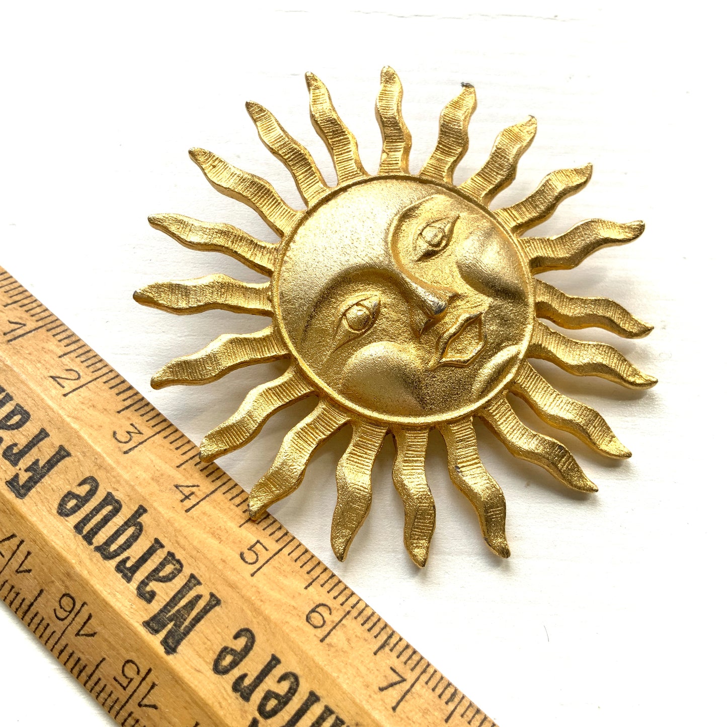 A charming vintage sun brooch featuring a smiling face.  笑顔をたたえた太陽のヴィンテージブローチ。