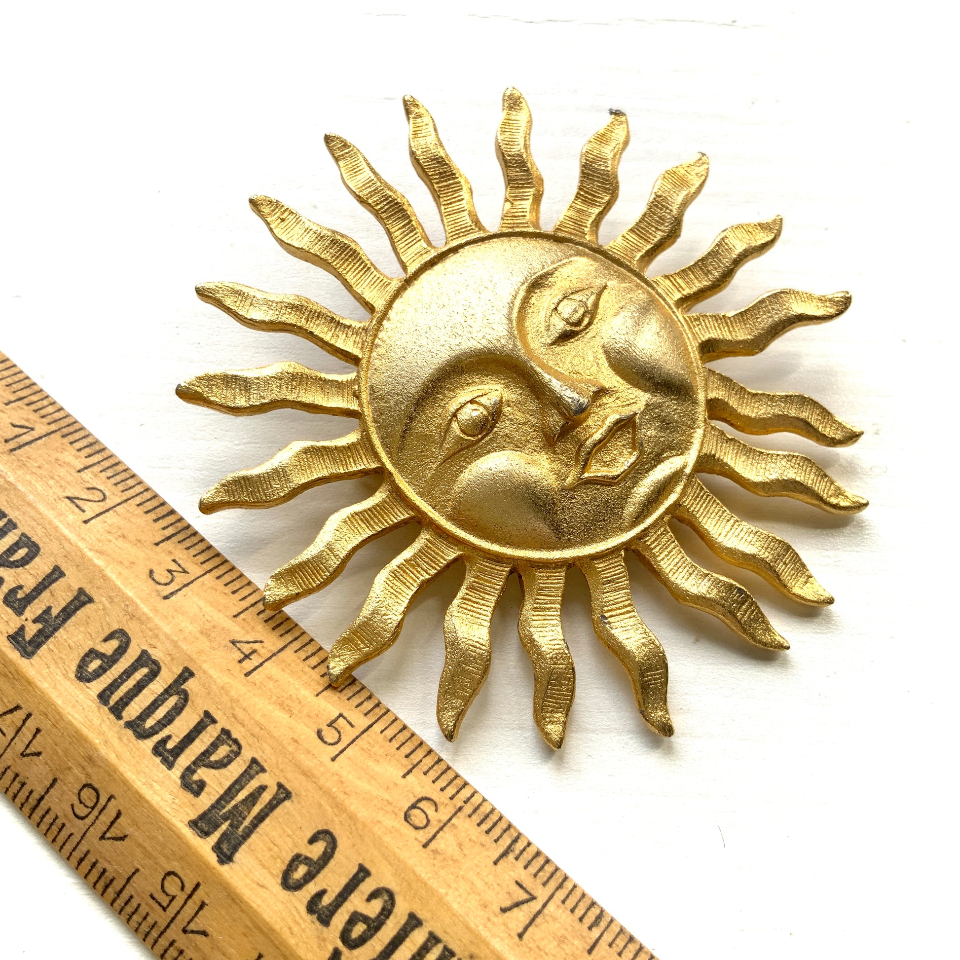 A charming vintage sun brooch featuring a smiling face.  笑顔をたたえた太陽のヴィンテージブローチ。