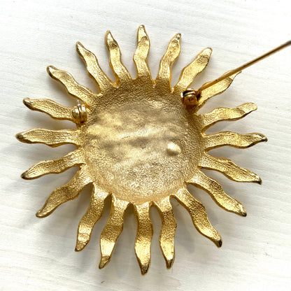 A charming vintage sun brooch featuring a smiling face.  笑顔をたたえた太陽のヴィンテージブローチ。