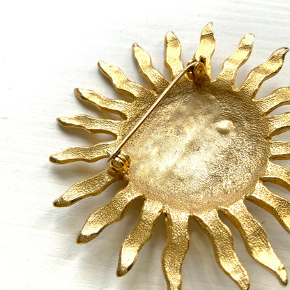 A charming vintage sun brooch featuring a smiling face.  笑顔をたたえた太陽のヴィンテージブローチ。