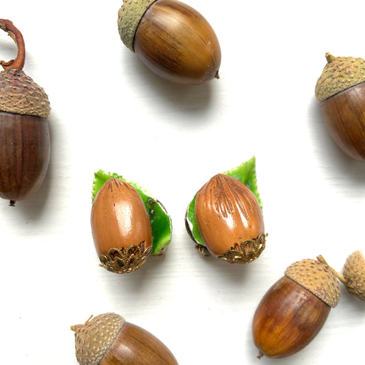 Realistic acorn clip-on earrings made of early plastic. Each acorn features fine carved-like grooves and delicate filigree metal caps at the base. プラスチック製の本物そっくりなどんぐりのクリップイヤリング。 