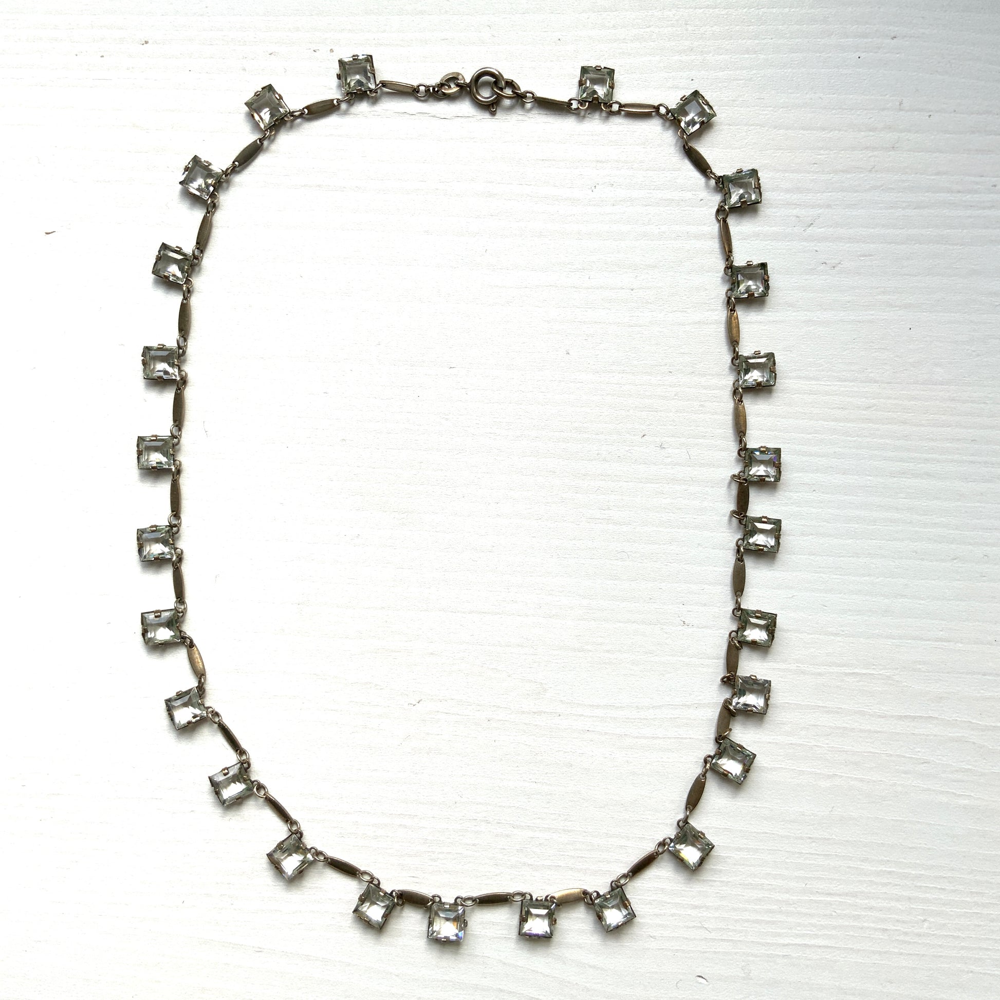 A classic Art Deco silver necklace set with square-cut clear glass stones. クラシックなスクエアカットのクリアグラスが並ぶ、アールデコのシルバーネックレス。