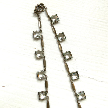 A classic Art Deco silver necklace set with square-cut clear glass stones. クラシックなスクエアカットのクリアグラスが並ぶ、アールデコのシルバーネックレス。