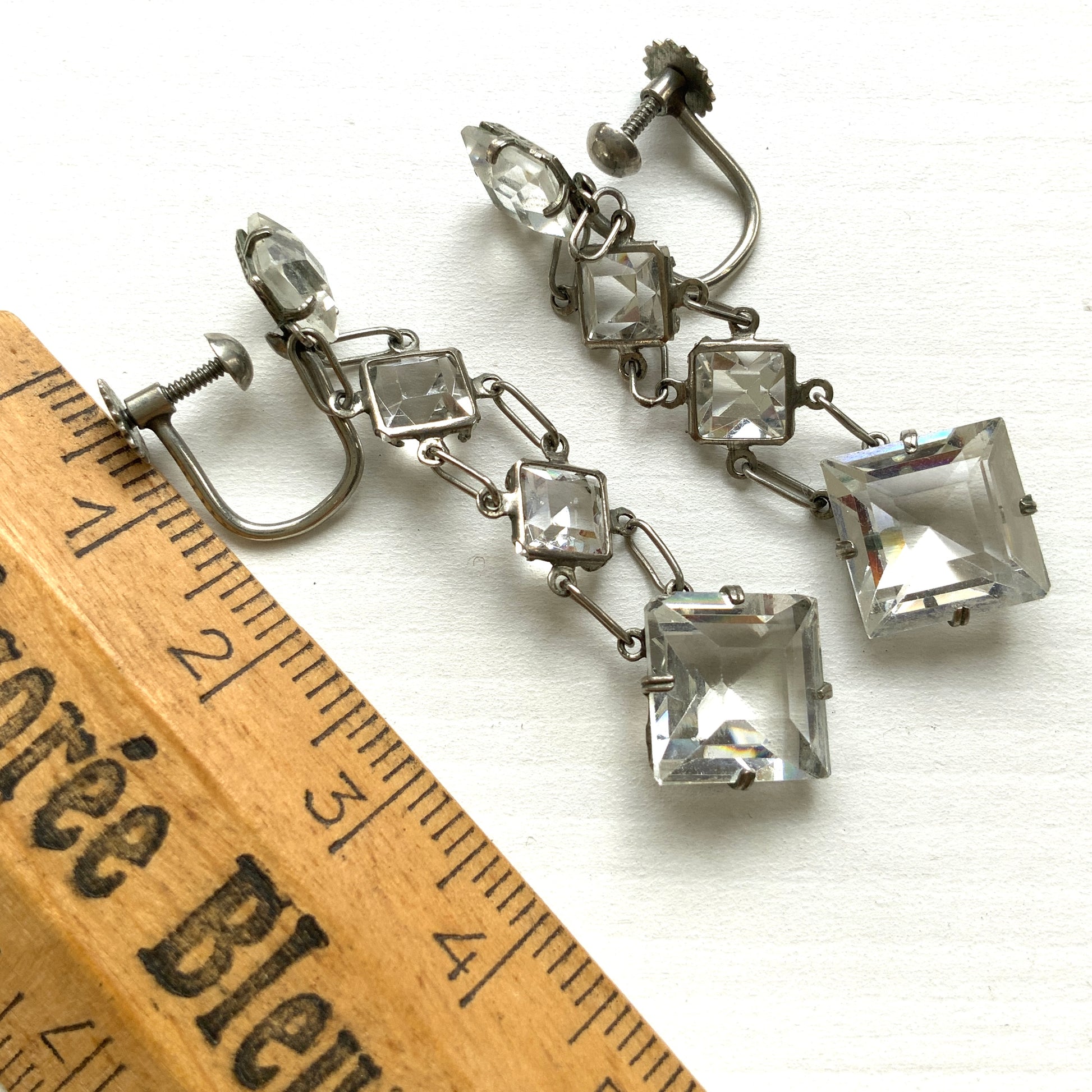 Screw-back earrings featuring clear diamond-shaped glass drops.クリアのダイヤ型グラスが揺れる、スクリューイヤリング。 
