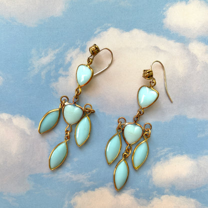 A pair of earrings featuring a pale turquoise heart glass chain adorned with marquise-shaped glass fringe. 淡いターコイズカラーのハートグラスチェーンに、マーキス 型のグラスのフリンジがついたピアス。 