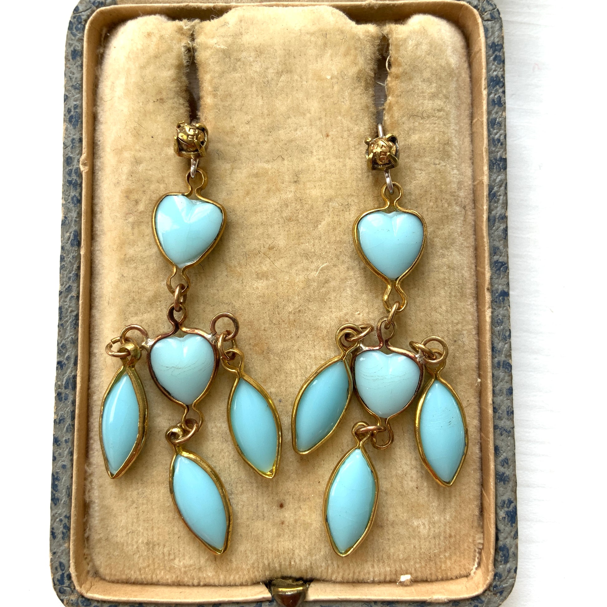 A pair of earrings featuring a pale turquoise heart glass chain adorned with marquise-shaped glass fringe. 淡いターコイズカラーのハートグラスチェーンに、マーキス 型のグラスのフリンジがついたピアス。 