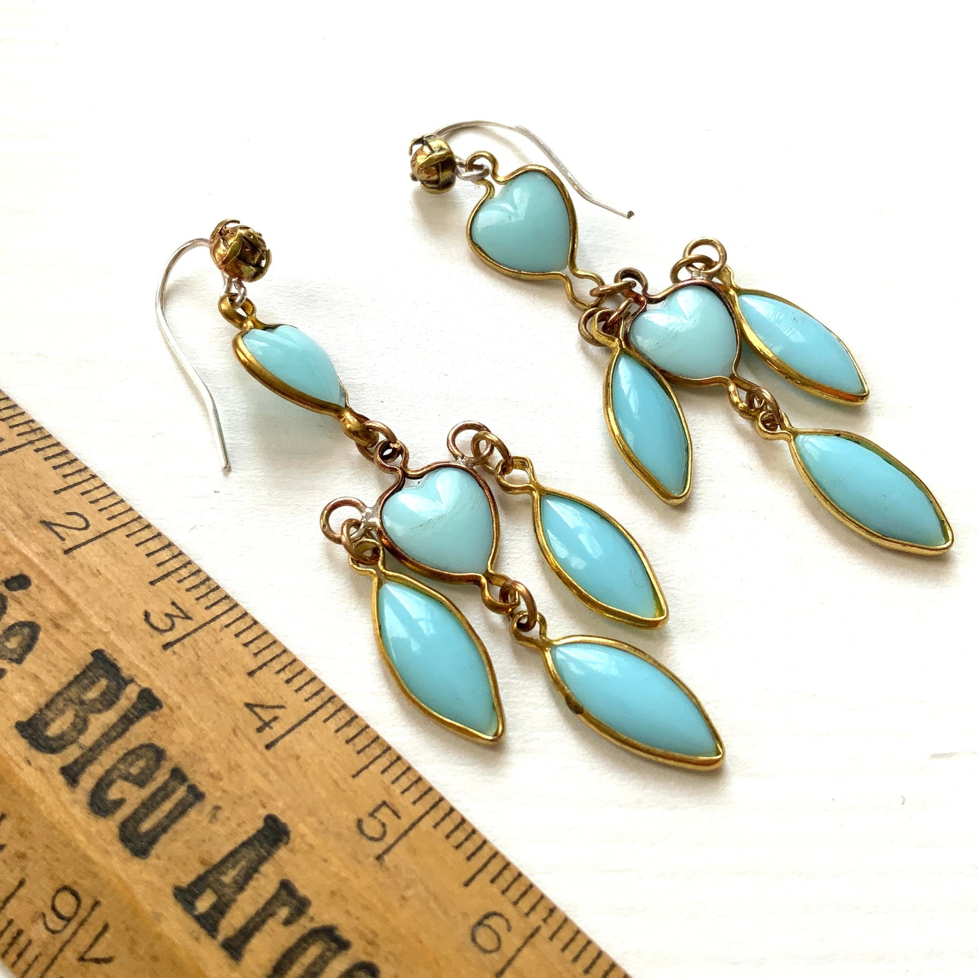 A pair of earrings featuring a pale turquoise heart glass chain adorned with marquise-shaped glass fringe. 淡いターコイズカラーのハートグラスチェーンに、マーキス 型のグラスのフリンジがついたピアス。 