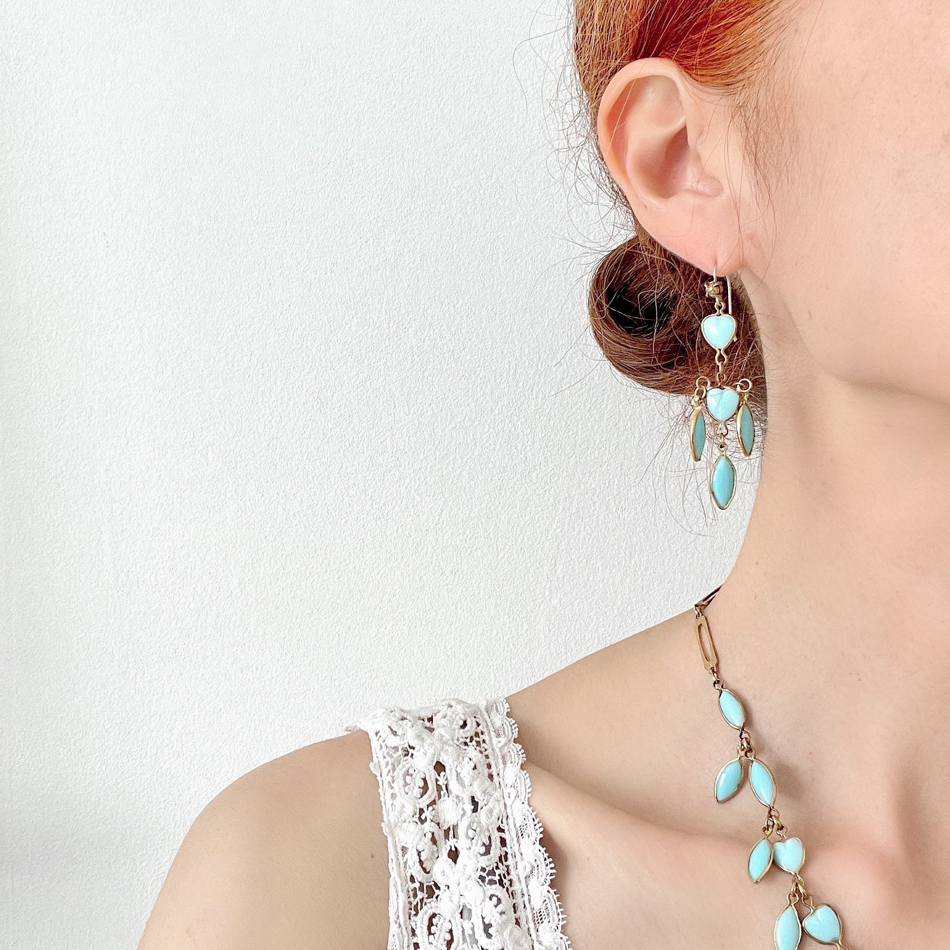 A pair of earrings featuring a pale turquoise heart glass chain adorned with marquise-shaped glass fringe. 淡いターコイズカラーのハートグラスチェーンに、マーキス 型のグラスのフリンジがついたピアス。 
