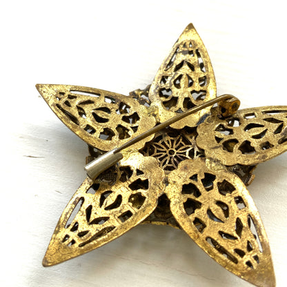 A beautiful vintage brooch featuring a star-shaped design crafted in intricate gold-tone filigree, adorned with multicoloured rhinestones. ゴールドトーンの繊細なフィリグリー細工でかたどられた星に、色とりどりのラインストーンがあしらわれたヴィンテージブローチ。 