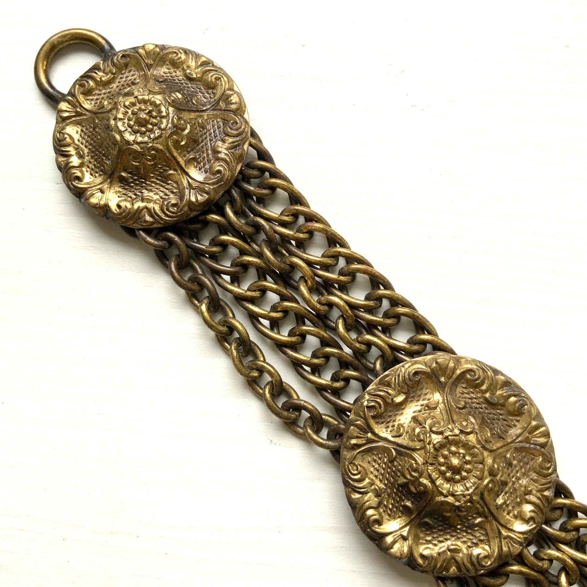 Brass bracelet featuring ornate floral discs linked with multiple chains. フローラルモチーフのメタルディスクと多連チェーンを組み合わせた、ブラス製ブレスレット。 
