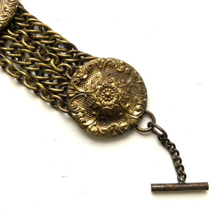 Brass bracelet featuring ornate floral discs linked with multiple chains. フローラルモチーフのメタルディスクと多連チェーンを組み合わせた、ブラス製ブレスレット。 