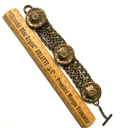Brass bracelet featuring ornate floral discs linked with multiple chains. フローラルモチーフのメタルディスクと多連チェーンを組み合わせた、ブラス製ブレスレット。 